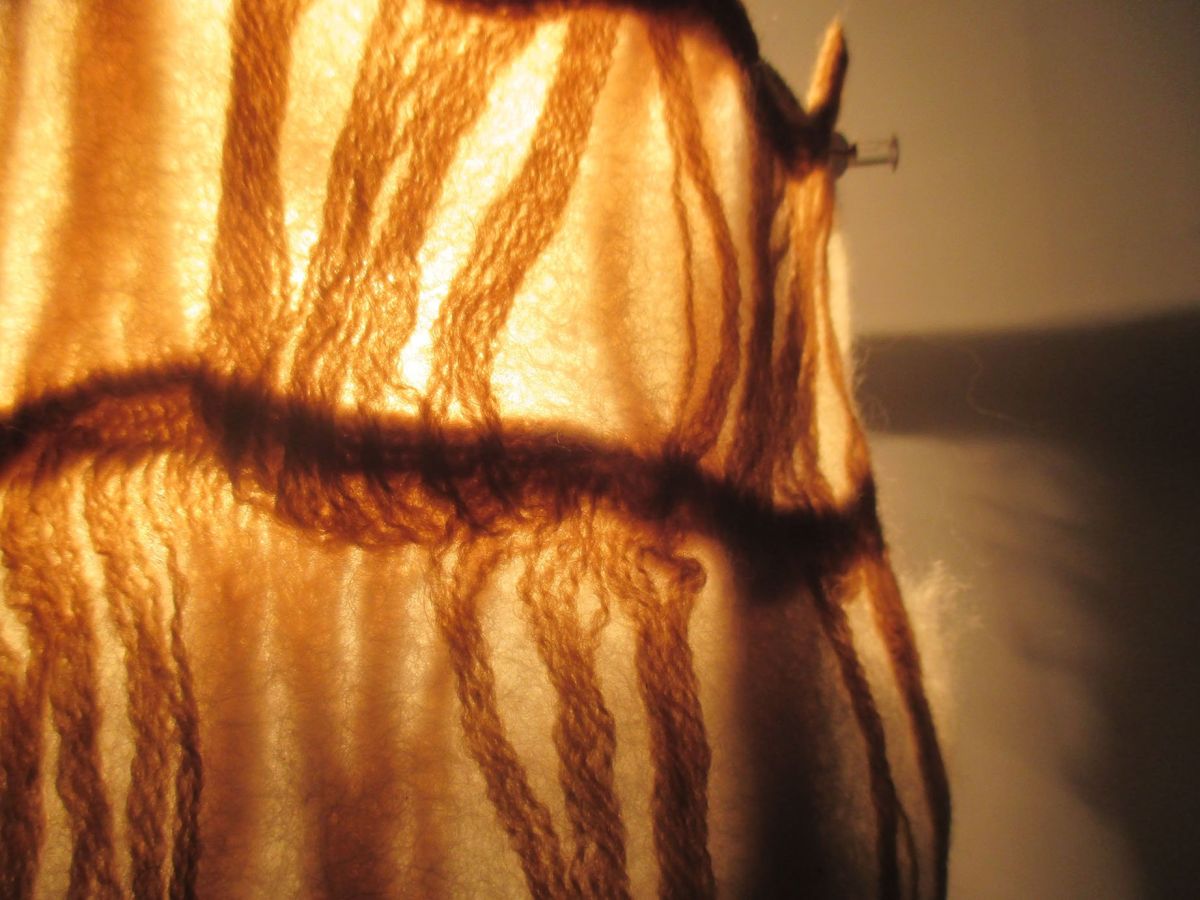 9 - Close up of wool felted through a piece of knit and held against artificial light